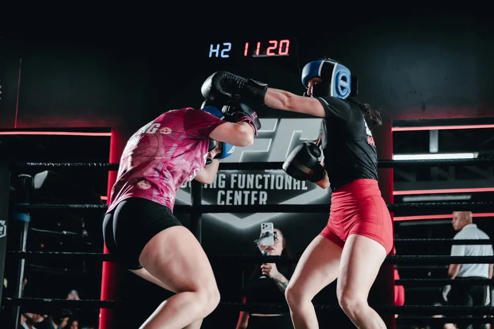 Dos boxeadoras con casco intercambian golpes en el ring de BFC
