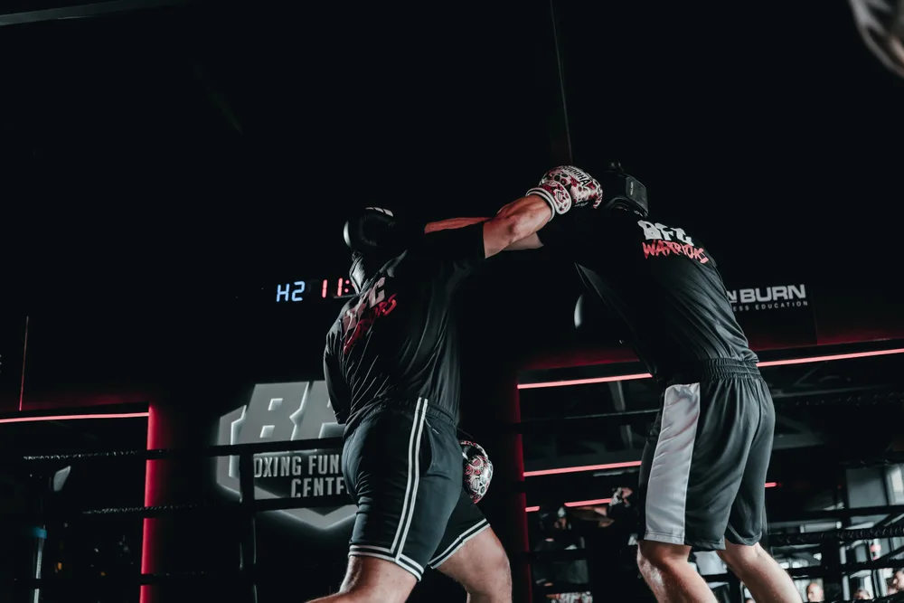 Dos boxeadores con camisetas de BFC Warriors se cruzan en el ring